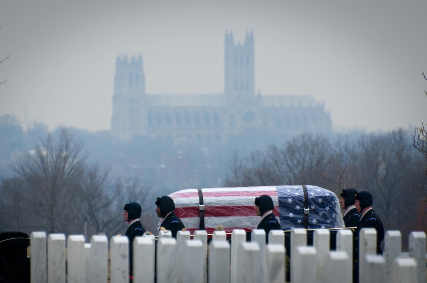 A casket in the snow passes under the shadow of the National Cathedral in Arlington National Cemetery in Arlington, Virginia.