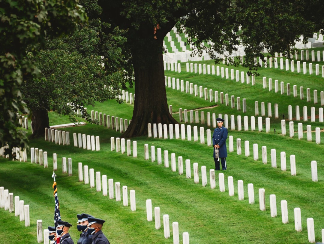 A US Air Force bugler stands in wait at a Full Honors service in Section 25 during a rainstorm in Arlington National Cemetery.