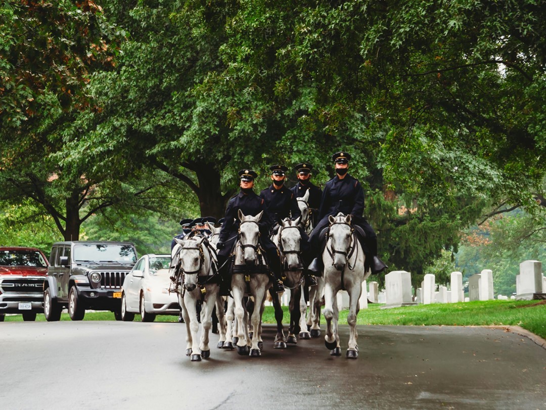 The US Army Caisson team pulls the honored remains of a fallen veteran in the rain through Arlington National Cemetery to their final resting place.

Six of the horses pull a flag draped casket on a black artillery caisson. Both Soldiers and horses are conscious that this is a serious and solemn final mission.  They have the honor of carrying a comrade for his last ride to Arlington National Cemetery, where he will rest in peace with other honored soldiers.

The solemn dignity which the riders and horses lend to this ceremony is neither accidental nor instinctive. Soldiers and horses train constantly for this duty. They are members of the Caisson platoon of the 3d United States Infantry "The Old Guard."