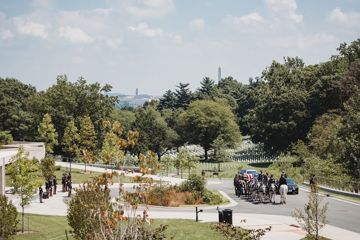 Washington DC, the Washington Monument, and the Lincoln Memorial can be seen behind a full honors service preparing to proceed to the gravesite in the Millennium Section of Arlington National Cemetery.