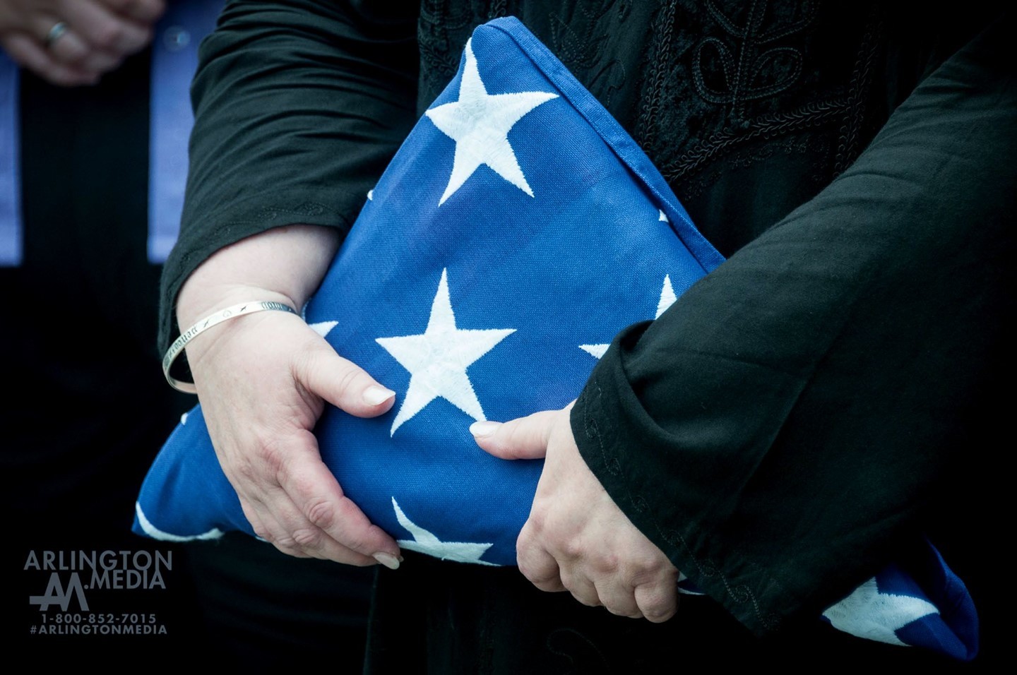 A folded flag is grasped by the family member of an honored veteran at a service captured by the @arlingtonmedia team.