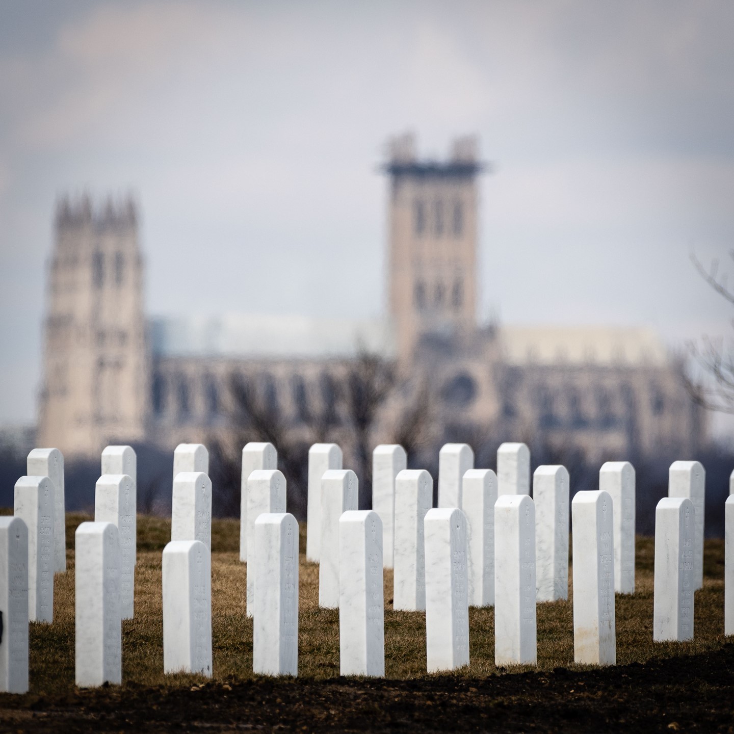 The National Cathedral is seen in the distance from Arlington National Cemetery.  Part of our goal in capturing your loved one's service at Arlington is to set the tone and tell a story.  We do this by not only capturing the service itself, the military honors, the folding of the flag, and the family and friends in attendance, but also by capturing the setting and the day.

For many, the trip to Arlington National Cemetery is no easy feat.  We want to honor your loved one by capturing the reverence of being surrounded by the Nation's Capitol as well as the rendering of honors.  Depending on the service location, we try to capture the setting as much as possible, and this can include the Washington Monument, Lincoln Memorial, Old Post Chapel, National Cathedral, and more, as shown here.