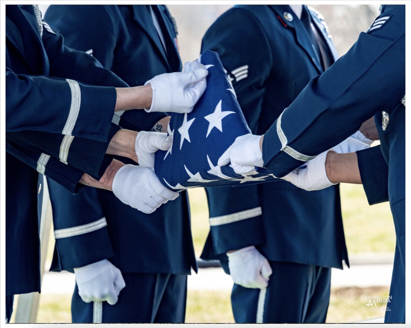 Airmen fold a flag in honor of a US Air Force veteran during a service in Arlington.  The flag is folded with precision, passed along the line of airmen, and presented with honors to the primary descendent.
