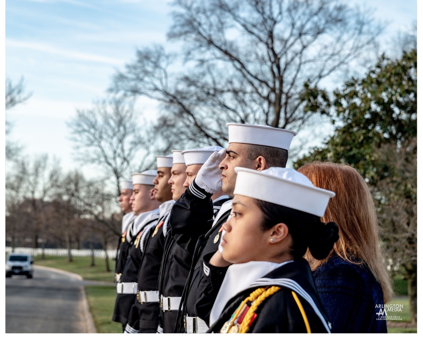 Sailors salute a funeral procession as they approach the gravesite at Arlington National Cemetery.